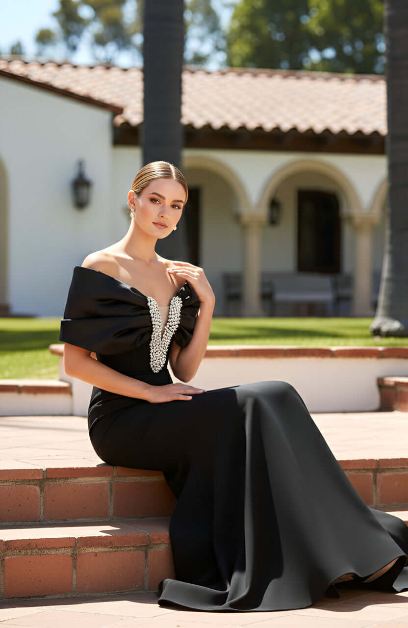 Model wearing black off-shoulder pearl evening dress with fitted silhouette