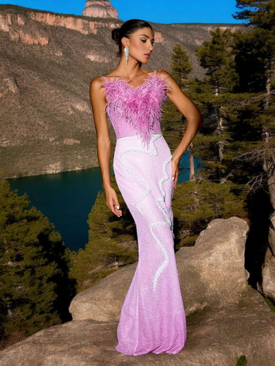 Woman wearing Feathers Patchwork Sparkling Sequins Maxi Dress in Pink, standing in front of a scenic mountain and lake background