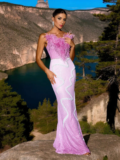 Woman wearing Feathers Patchwork Sparkling Sequins Maxi Dress in Pink, standing outdoors with scenic landscape background